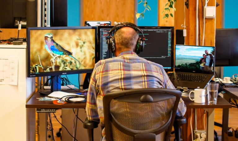 a man sitting at a desk with multiple monitors